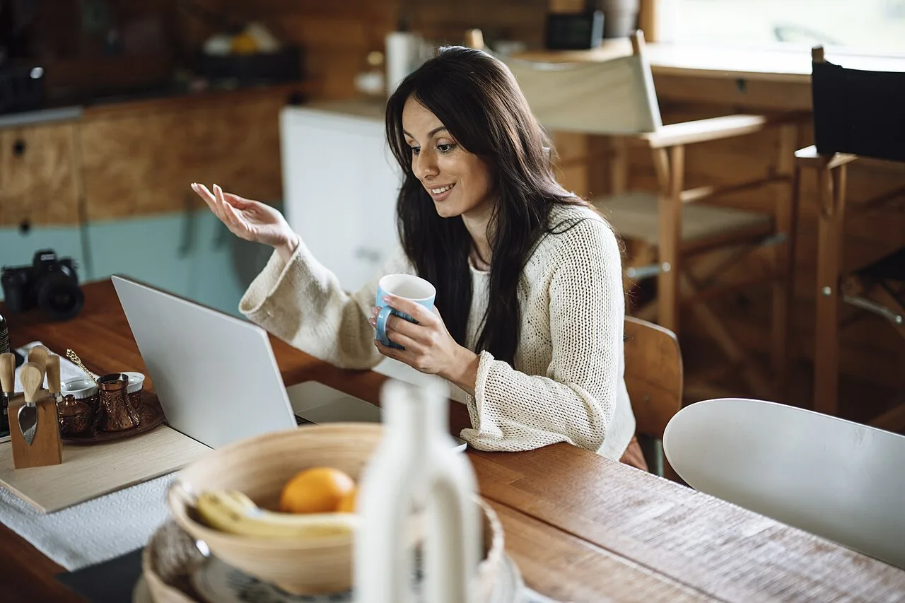Woman talking beside a laptop in a home live video setting