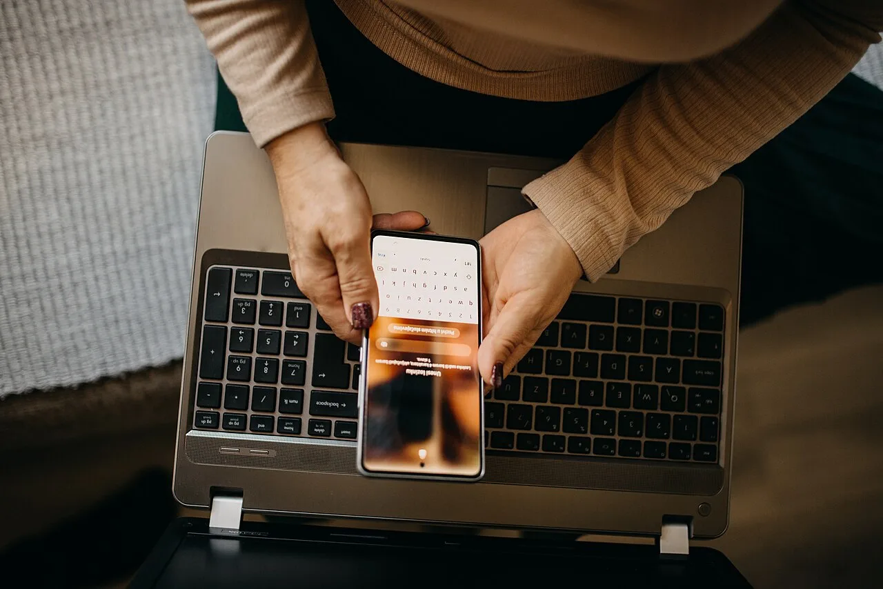 Woman using a smartphone and laptop to browse live video