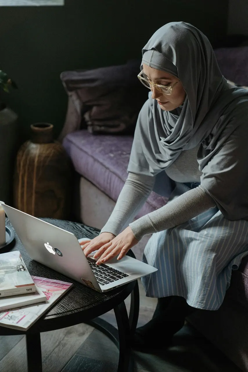 A woman using a laptop while relaxing on a sofa at home